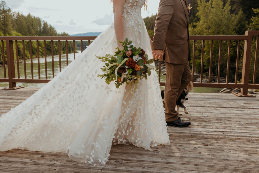 Couple walking across a bridge in wedding attire.
